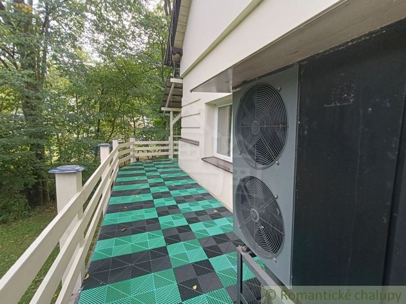 A family house in Staškov has a terrace with colorful tiles and surrounding trees.