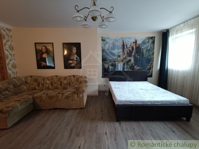 A room in a family house with a bed, a sofa, and pictures on the wall.