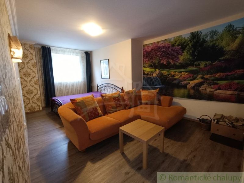 Living room in a family house with an orange sofa and nature wallpaper.
