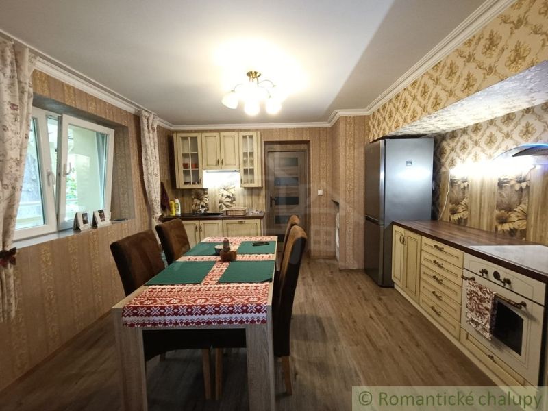 A kitchen in a family house with patterned wallpaper and a wooden decor floor.
