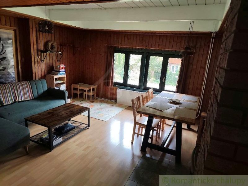 Living room in a cottage with wood-patterned flooring and a dining area.