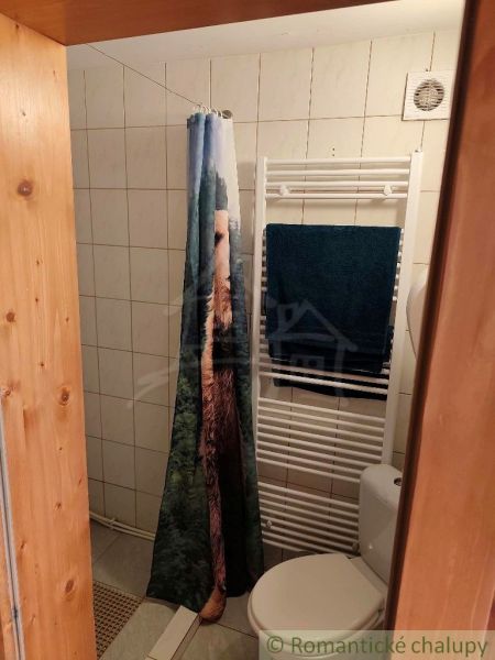 A bathroom in a cabin with a tiled wall, a curtain, and a heating element.