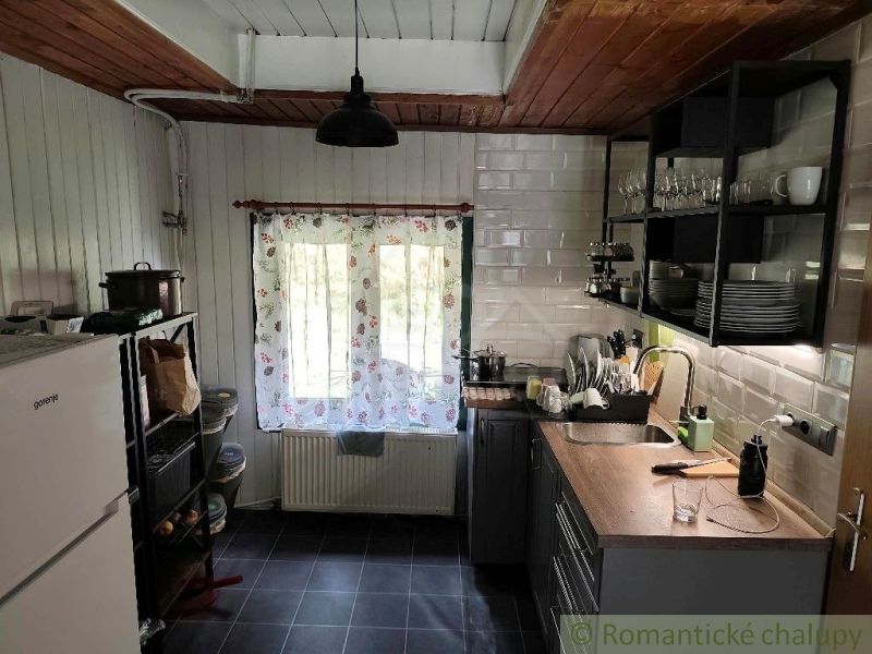 A kitchen in a cottage with a rustic atmosphere and wooden decor on the ceiling.