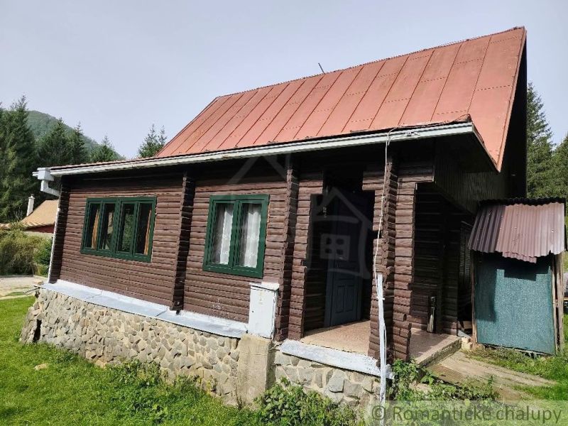 A wooden cottage with a metal roof in the nature of Rajecká Lesná, surrounded by greenery.