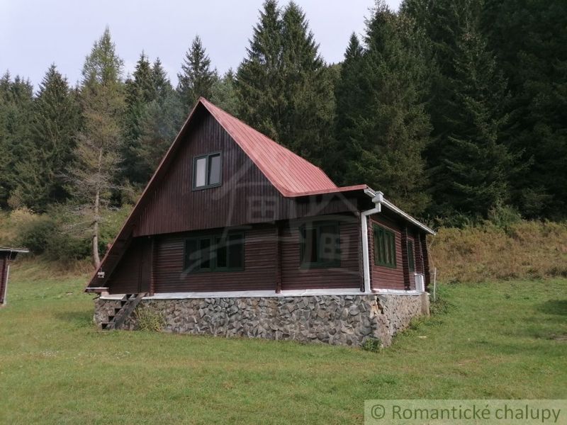 A cottage in Rajecká Lesná surrounded by forest, with a stone foundation and a roof.