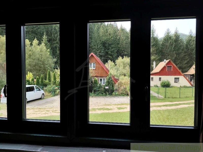View of cottages in Rajecká Lesná, surrounded by greenery and cars.