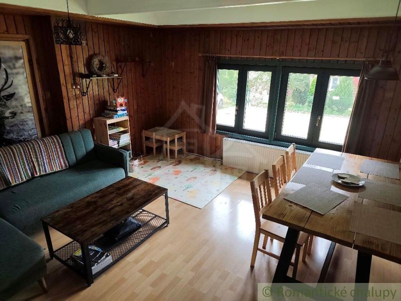 The living room of the cottage with a comfortable sofa and a table, wooden decor flooring.