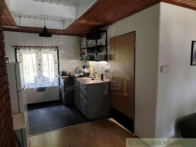Kitchen area in a cabin with wooden floor decor and brick wall.