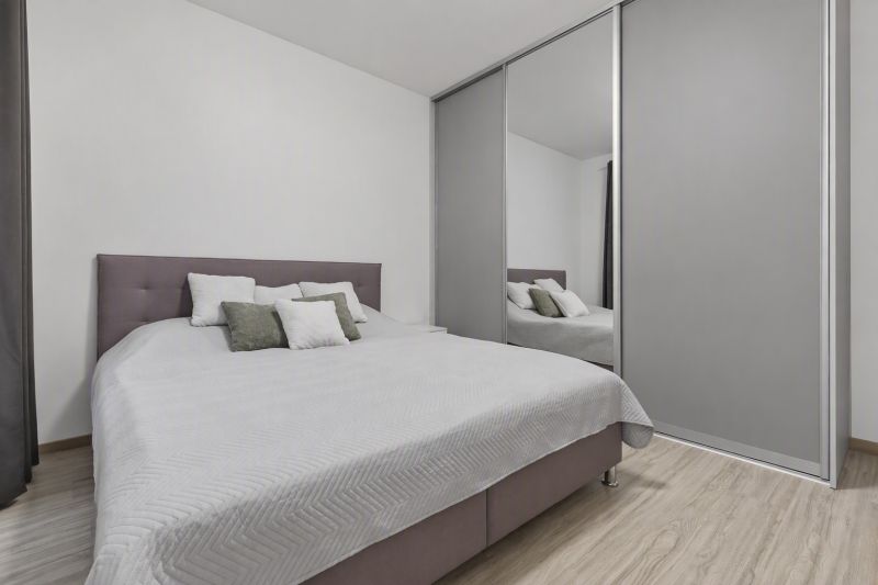 A bedroom with a large bed, built-in wardrobe, and wooden decor flooring in a two-room apartment.