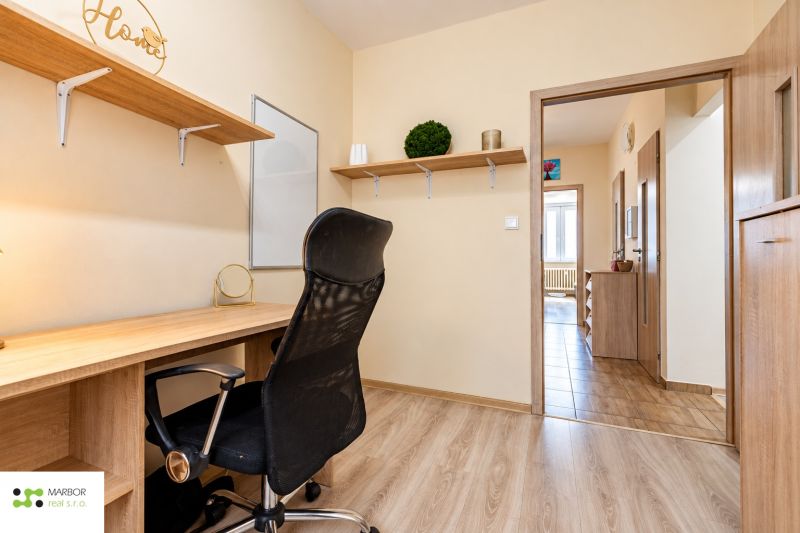 A workspace with a desk and a black office chair, complemented by a floor with a wooden decor.