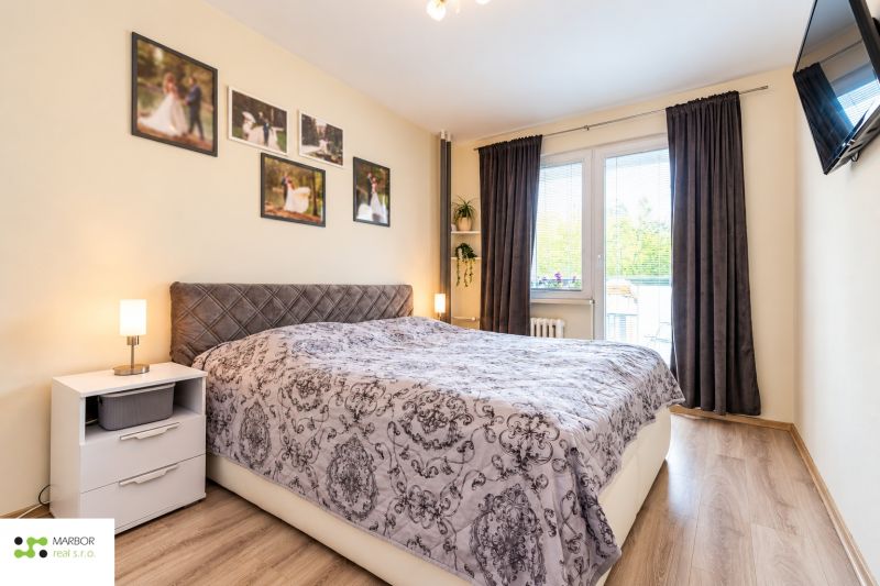 A bedroom with a decorative bed, a nightstand, and curtains in a three-room apartment.