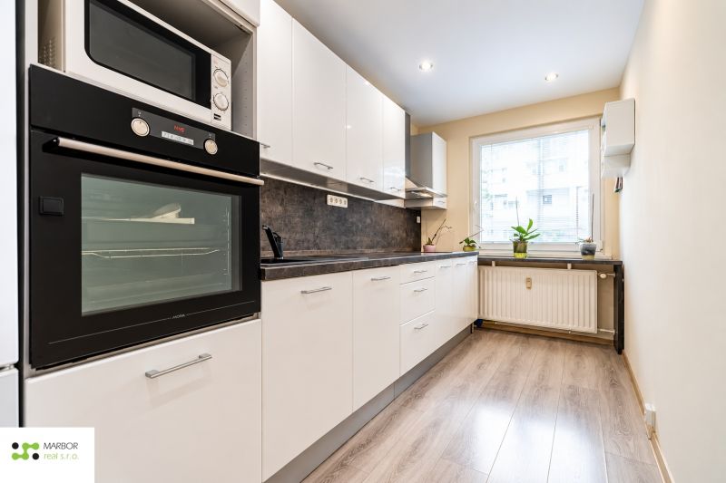 A kitchen in a 3-room apartment with white cabinets and a wood-patterned floor.