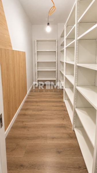 Storage space with white shelves and a wooden decor floor in a 2-room apartment.