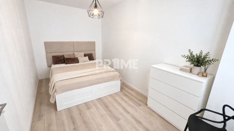 A room in a 2-room apartment with a bed, a dresser, and a floor with a wood decor.