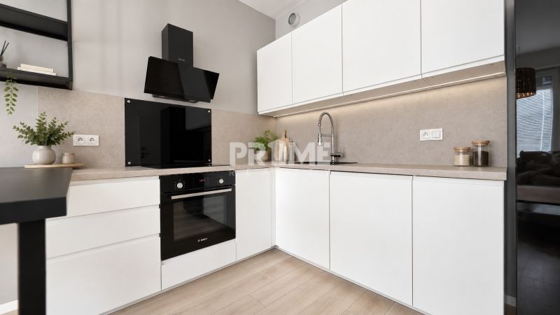 A kitchen in a 2-room apartment with white cabinets and a wood-patterned floor.