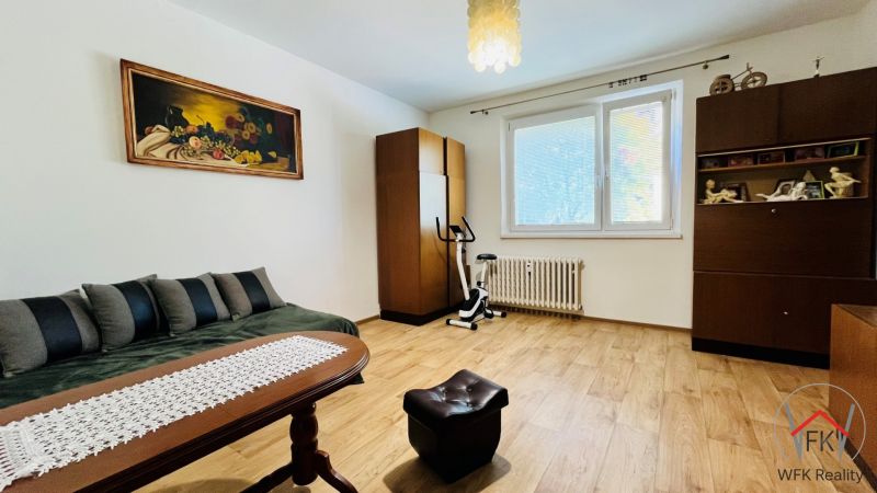 A room in a 3-room apartment with a wooden decor floor, vintage furniture, and a painting on the wall.