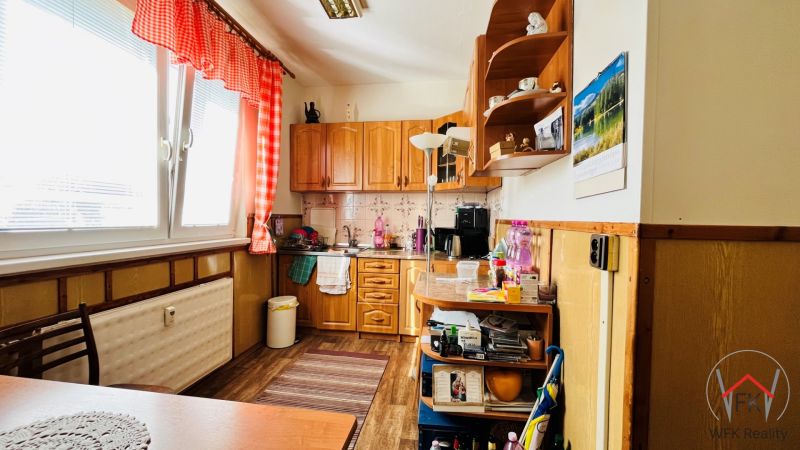 A kitchen in a 3-room apartment, with a wooden decor floor, red curtains, and equipment.