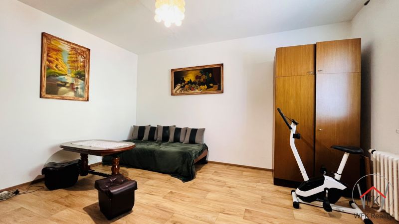 A room in a 3-room apartment with a sofa, a table, and a floor with a wooden decor.