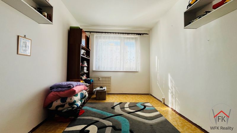 A simple room in a 3-room apartment with a carpet and a shelf by the window.