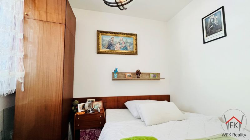 A bedroom in a three-room apartment with a picture and a spotlight shelf above the bed.