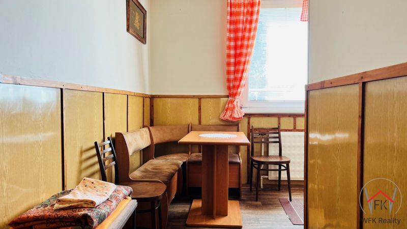 A kitchenette in a 3-room apartment with wooden decor and seating with a table.