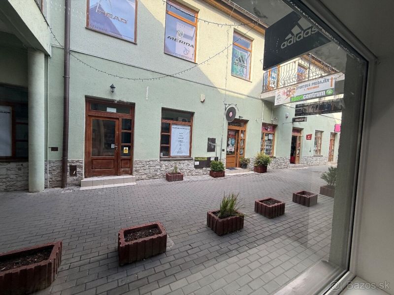 Commercial premises in Topoľčany with stone cladding and flower pots on a paved street.