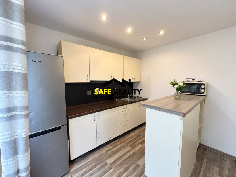 A kitchen with a wood-patterned floor, light cabinets, and a refrigerator in a studio apartment.