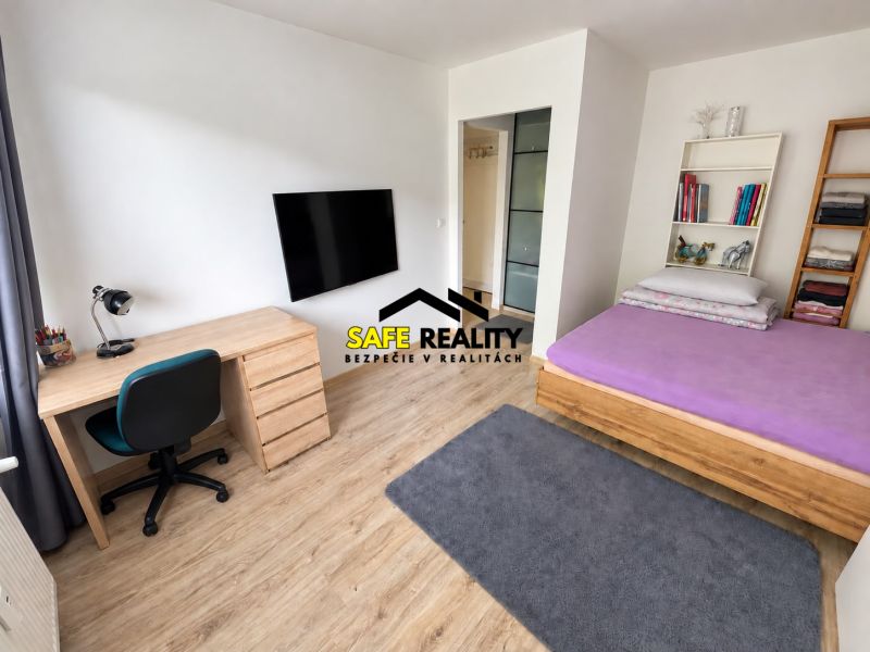 Interior of a 1-room apartment with a table, television, and bed, floor with wooden decor.