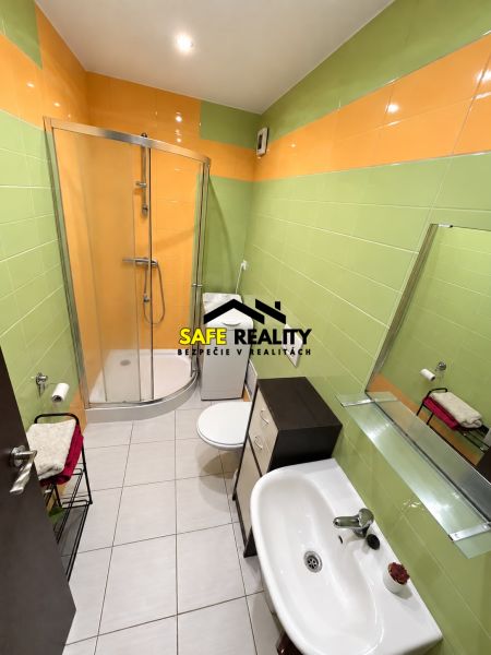 A bathroom with colorful tiles and a shower in a studio apartment.