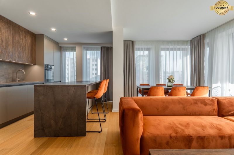 Interior with wood-patterned flooring, orange sofa, and dining table. Apartment construction.