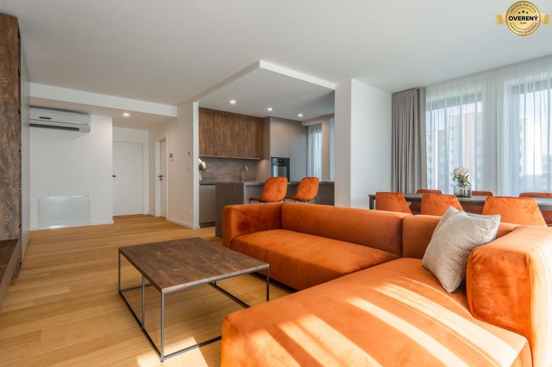 Living room with an orange sofa, kitchen, and wooden decor flooring in the apartment construction project.