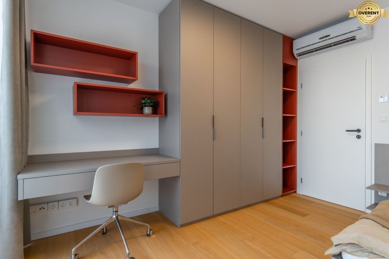 Interior with an office desk, storage cabinets, and a wood-patterned floor. Apartment construction.