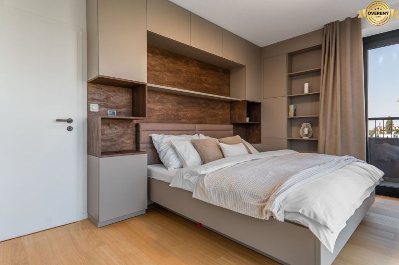 A bedroom in an apartment with modern cabinets and a wooden decor floor.