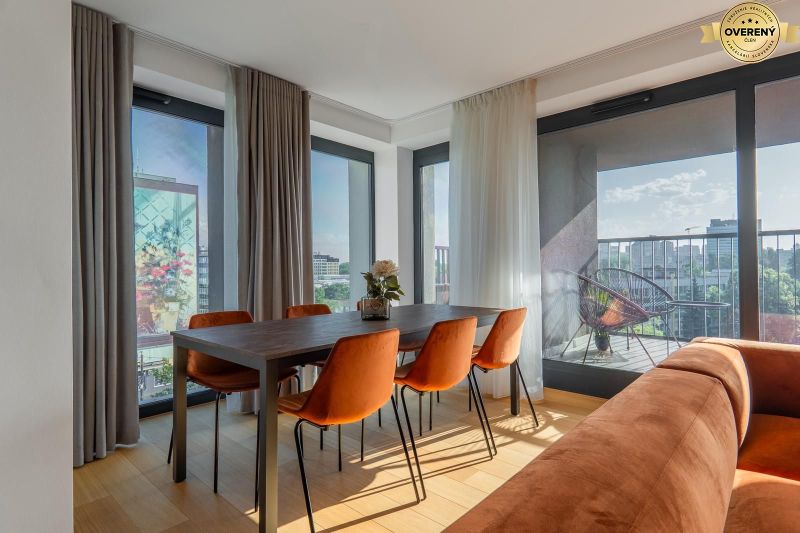 Dining area with orange chairs, wooden decor flooring, access to the balcony. Apartment construction.