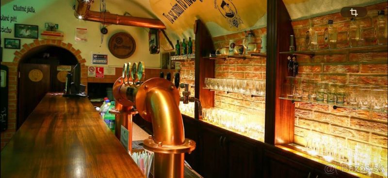 A bar counter in a gastro space with a brick wall and brass taps.