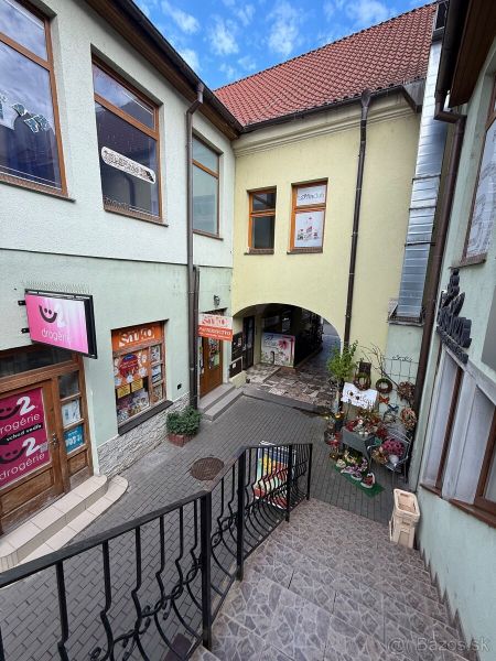 The stairs lead to commercial premises in the historic center of Topoľčany, surrounded by shops.