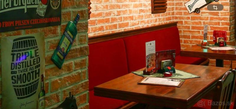 A brick wall and wooden furniture in the dining area with red seating add coziness.