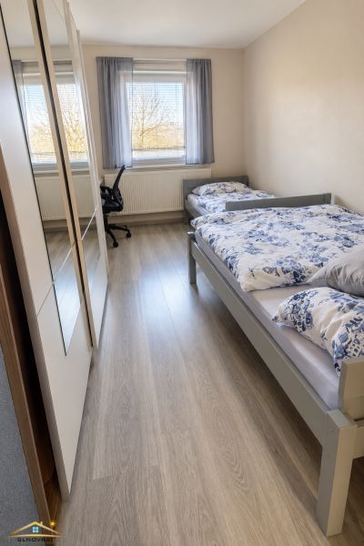 A room with two beds and a wooden decor floor in a family house.
