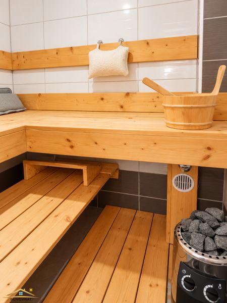 A sauna in a family house with wooden paneling and a stove with stones.