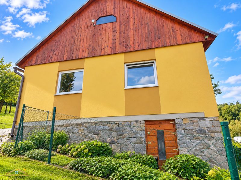 The family house on Košariská Street in Oščadnica has a yellow facade and a stone foundation.
