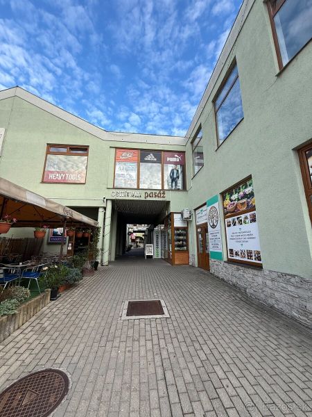 Commercial spaces in Topoľčany with an open passage and outdoor advertisements.