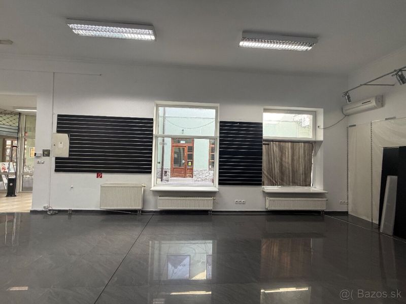 Commercial space with a gray floor and a large window.