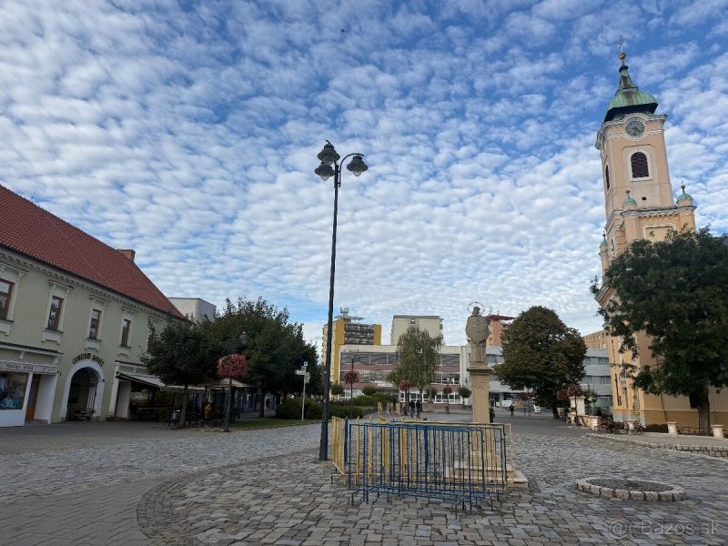 Commercial premises in Topoľčany with a paved square and a church in the background.