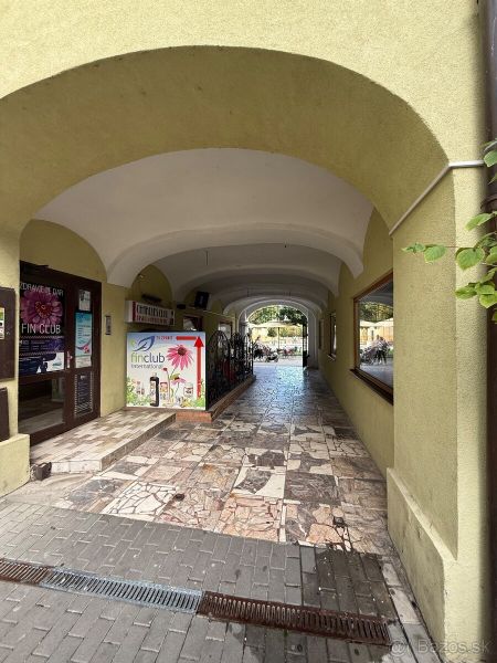 An arched underpass leading to the dining areas in Topoľčany with stone paving.
