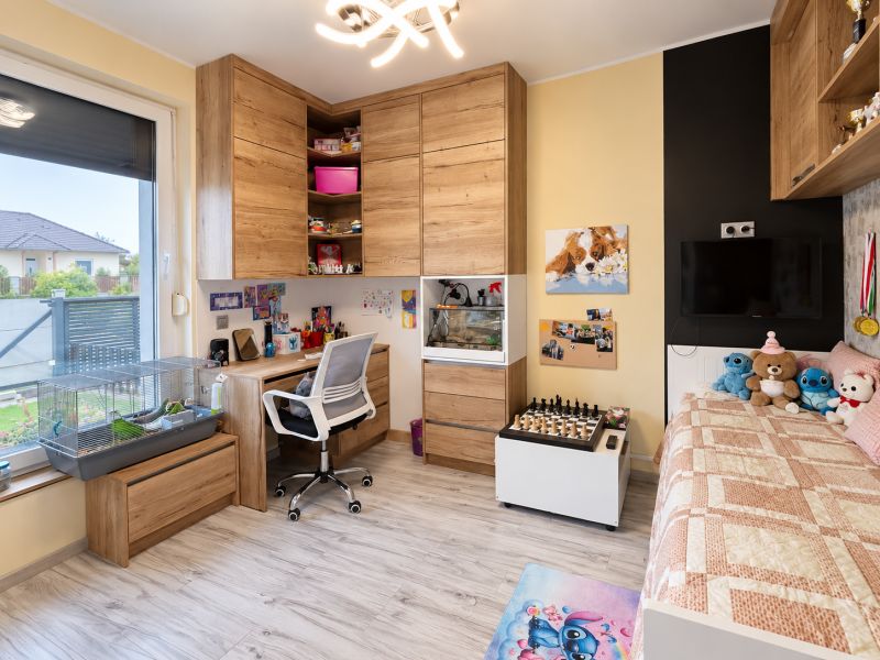 Children's room with wood-patterned flooring, a bed, and a desk in a family house.