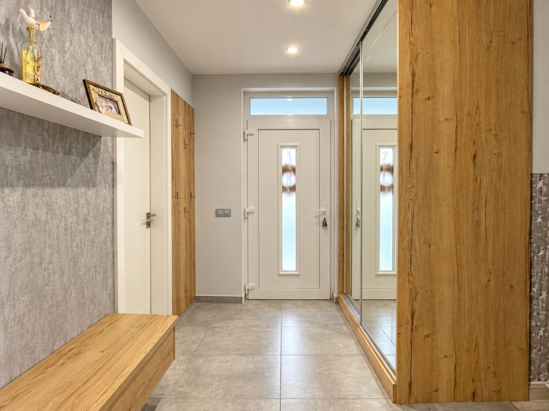 Interior of a family house with wooden decor and a large mirror in the hallway.