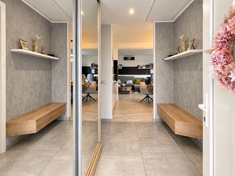 A hallway with shelves and a bench, a floor with a wooden decor in a family house.
