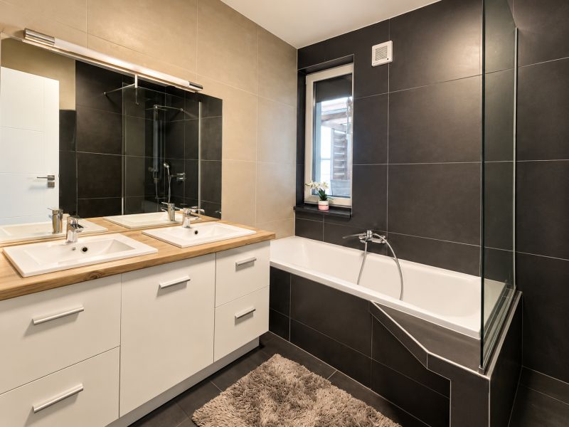 A bathroom in a family house with a double sink and a bathtub, light tiles.