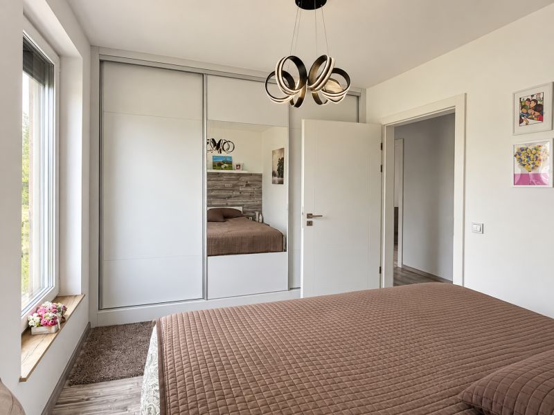 A bedroom in a family house with a large built-in wardrobe and a floor with a wooden decor.