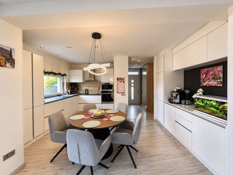 Interior of a family house with a kitchen, dining table, and wooden decor flooring.